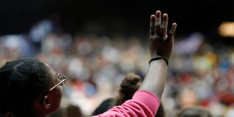 Woman holds hand up in the air during religious event