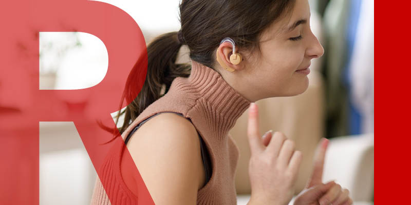 A young person with hearing aids, their index fingers in the air by their face