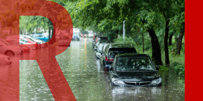 Parked cars on a flooded street - the water goes up to their headlights.