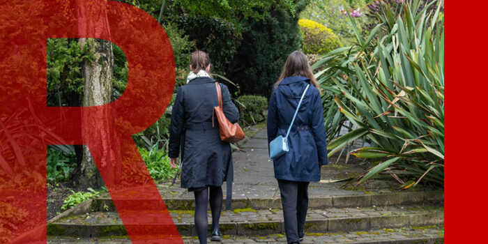 Two women walking on a path in a park, picture taken from the back