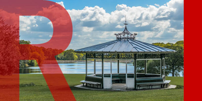 A bandstand in a park in front of a large pond