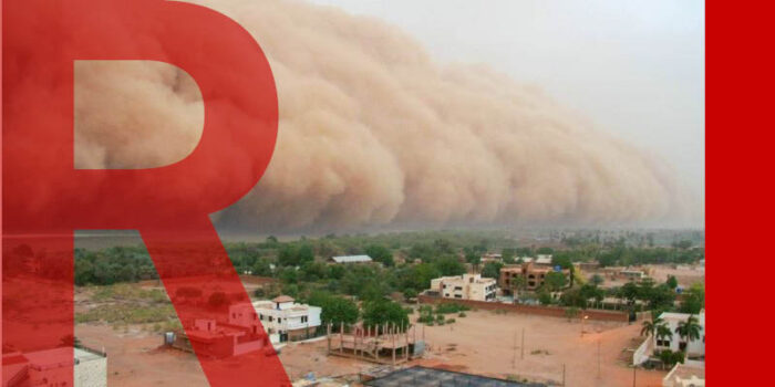 A village on the edge of a desert about to be engulfed by a sandstorm.