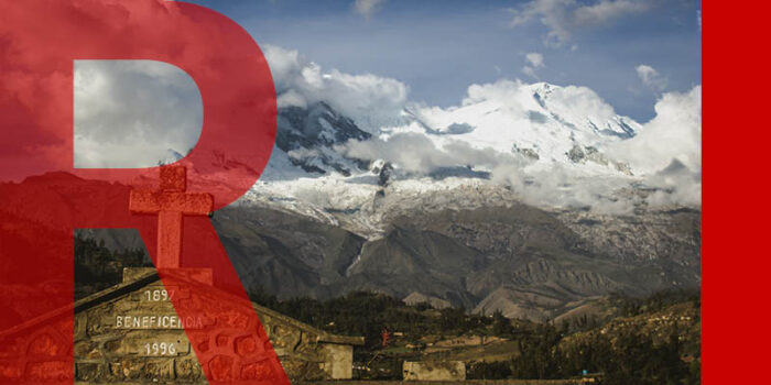 The roof of a Christian monument, with a stone cross, in front of a large snow-capped mountain in Yungay, Peru