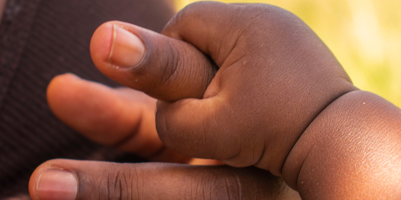 Baby holds adult hand