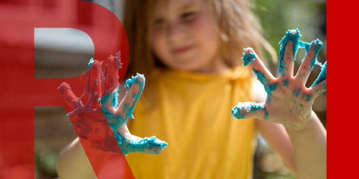 A young child holding hands out in front of them, covered in blue playdoh