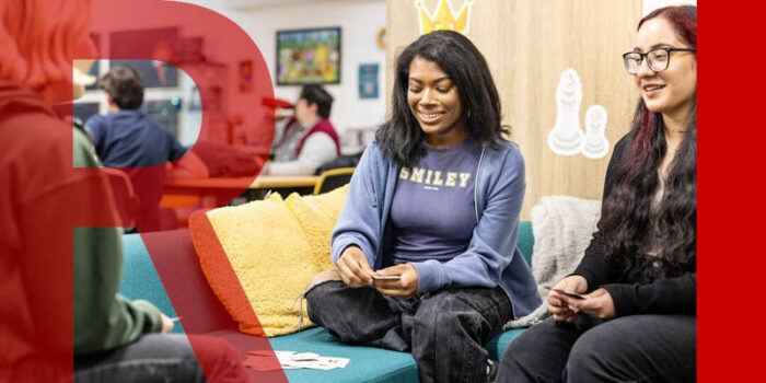 Three young adults playing cards on a sofa